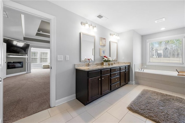 full bathroom featuring a sink, double vanity, tile patterned flooring, and a glass covered fireplace