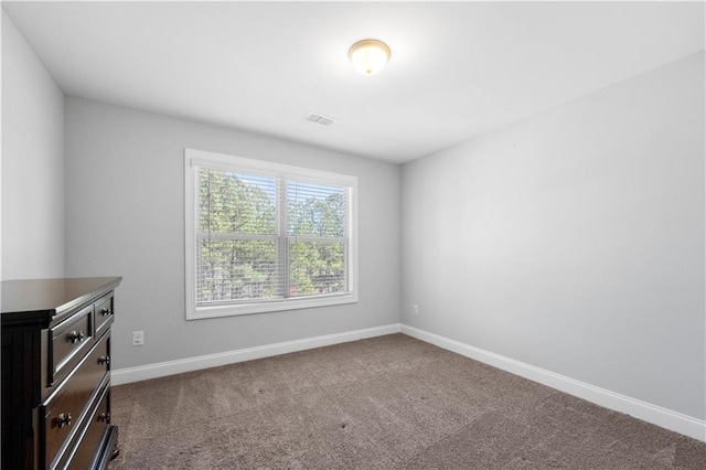 spare room featuring carpet floors, visible vents, and baseboards