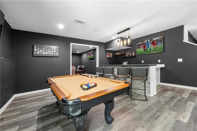 rec room with indoor bar, wood finished floors, visible vents, and baseboards