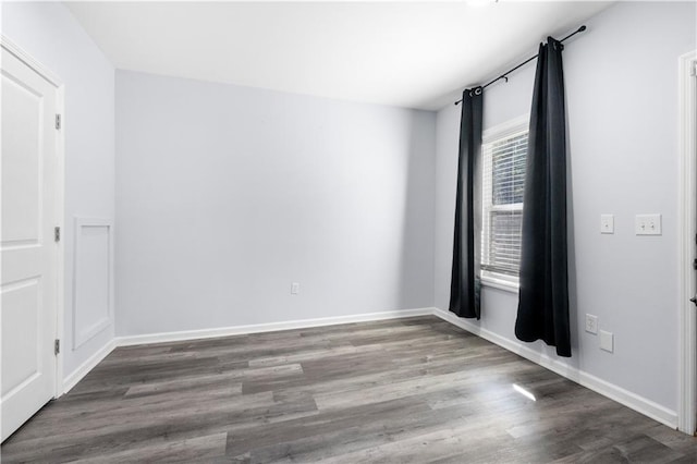 spare room with baseboards and wood finished floors