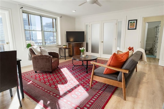 living room featuring light wood-type flooring, a ceiling fan, and french doors