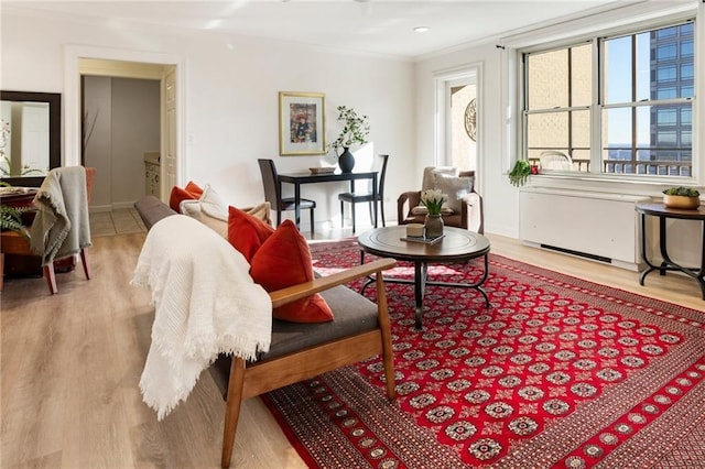 living room featuring light wood-style flooring, radiator heating unit, and crown molding