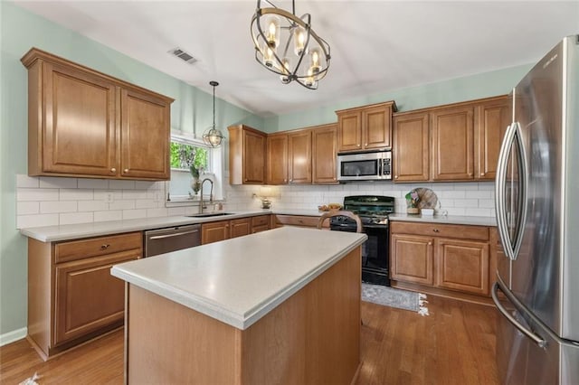 5415 Fieldfreen Dr, Cumming, GA 30028 - kitchen featuring appliances with stainless steel finishes, a sink, brown cabinets, dark wood-style floors, and tasteful backsplash
