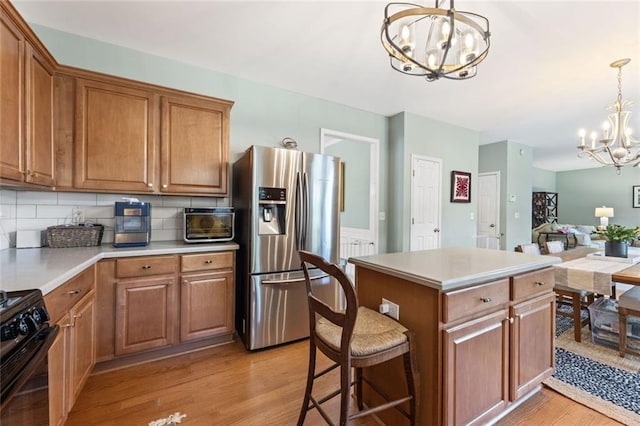 5415 Fieldfreen Dr, Cumming, GA 30028 - kitchen featuring a chandelier, stainless steel fridge with ice dispenser, gas stove, light wood-style floors, and brown cabinetry