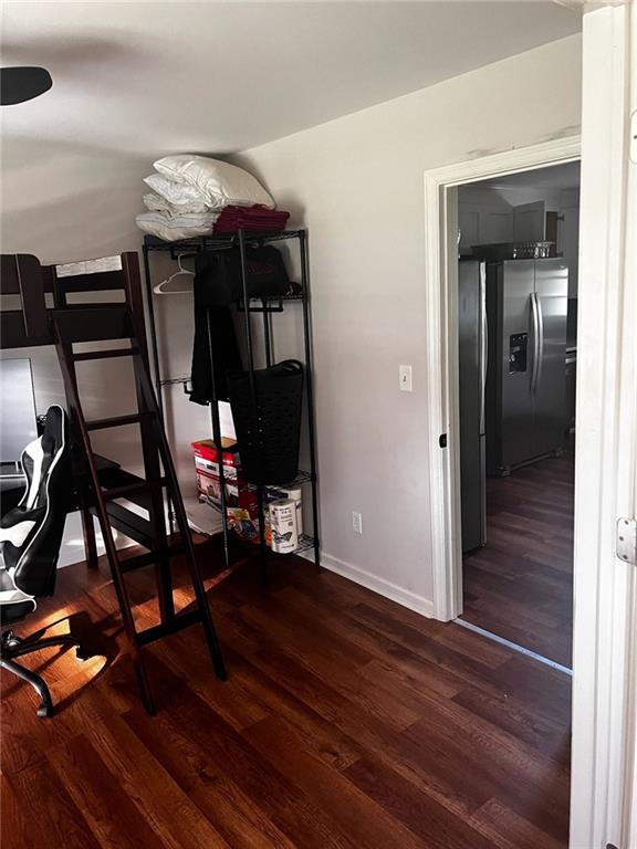 bedroom featuring wood finished floors, stainless steel fridge with ice dispenser, and baseboards