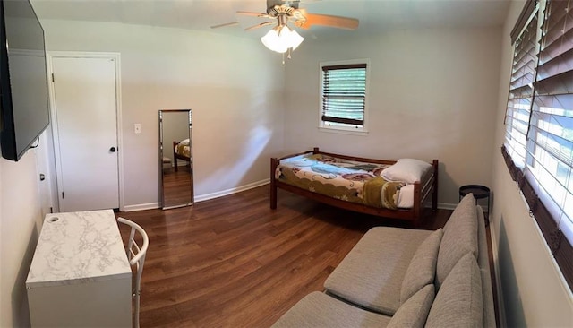 bedroom with dark wood finished floors, a ceiling fan, and baseboards