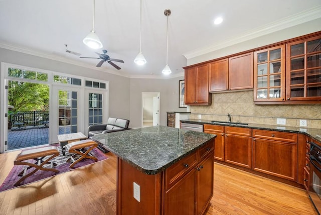 kitchen featuring sink, light wood-type flooring, ornamental molding, decorative light fixtures, and a kitchen island