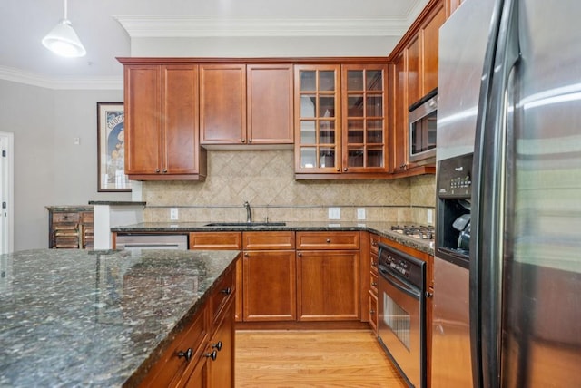 kitchen featuring stainless steel appliances, crown molding, sink, pendant lighting, and light hardwood / wood-style flooring