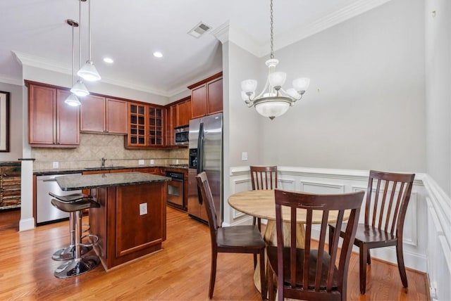 kitchen featuring pendant lighting, a kitchen island, light wood-type flooring, and appliances with stainless steel finishes