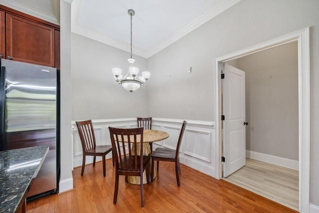 dining room with a notable chandelier, light wood-type flooring, and ornamental molding