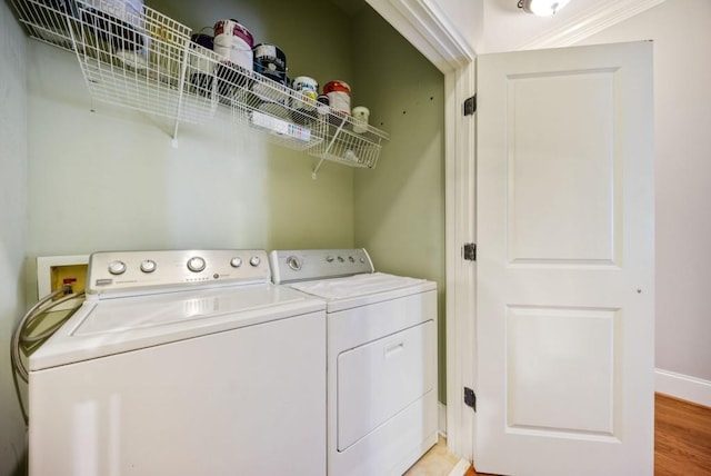 clothes washing area with separate washer and dryer, ornamental molding, and light wood-type flooring