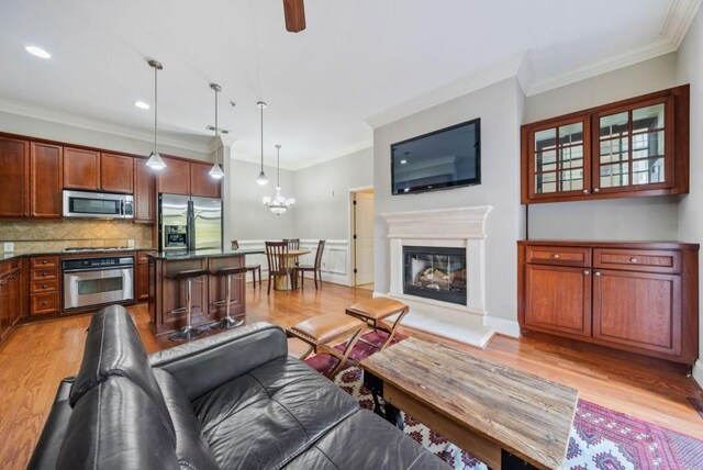 living room with crown molding, ceiling fan, and light wood-type flooring