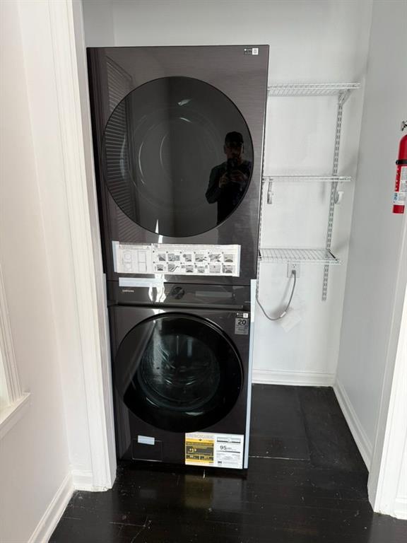 washroom with dark wood-type flooring and stacked washer and clothes dryer