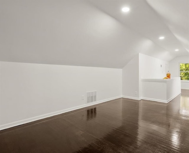 additional living space with vaulted ceiling and dark wood-type flooring