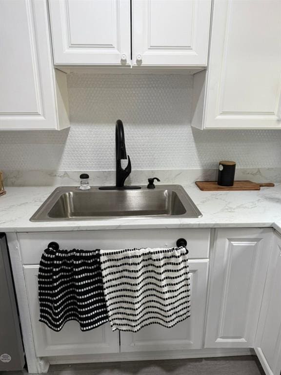 room details with dishwasher, white cabinets, sink, and light stone countertops