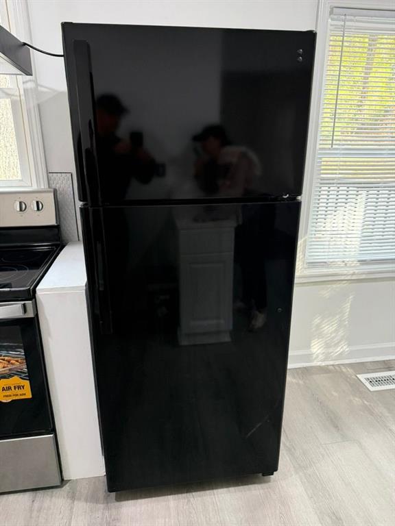 kitchen featuring black refrigerator, light hardwood / wood-style floors, and stainless steel electric range