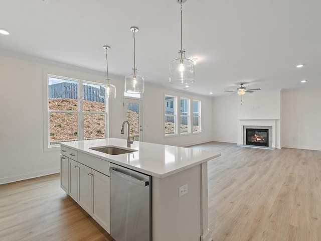 kitchen featuring white cabinets, sink, hanging light fixtures, a kitchen island with sink, and stainless steel dishwasher