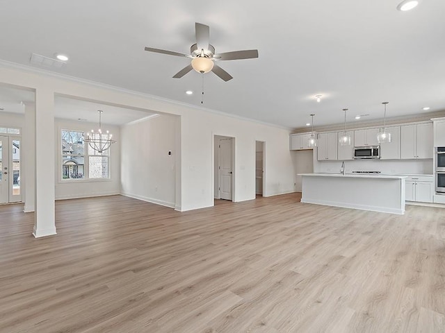 unfurnished living room with crown molding, ceiling fan with notable chandelier, light hardwood / wood-style flooring, and sink