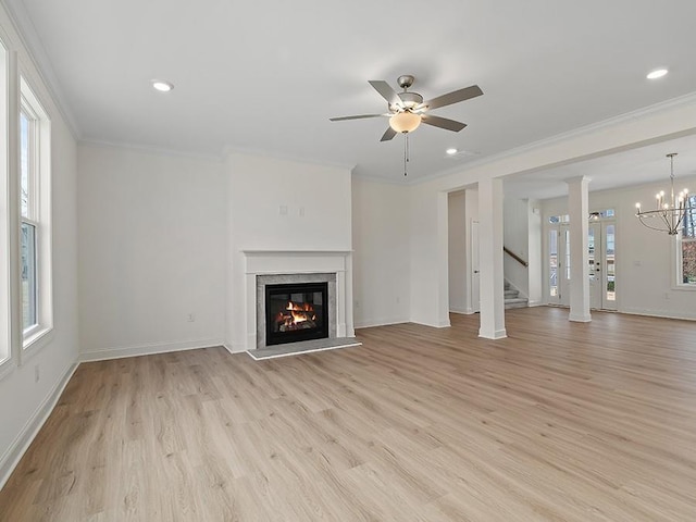 unfurnished living room featuring ceiling fan with notable chandelier, plenty of natural light, and ornamental molding