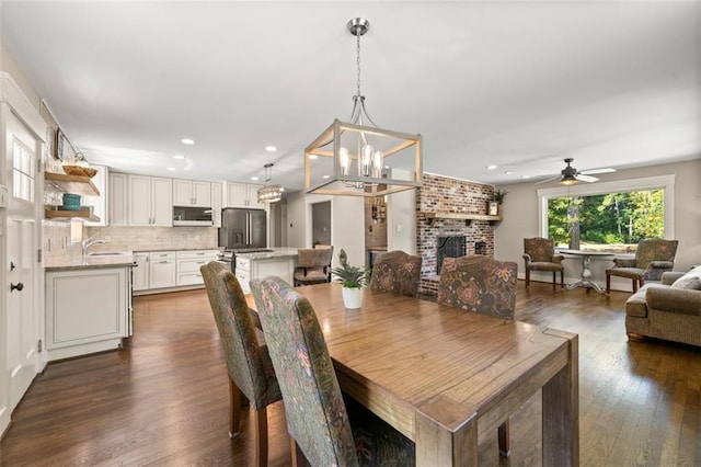 1382 Varner Rd, Marietta, GA 30062 - dining room featuring dark wood-type flooring, a chandelier, a ceiling fan, a brick fireplace, and recessed lighting