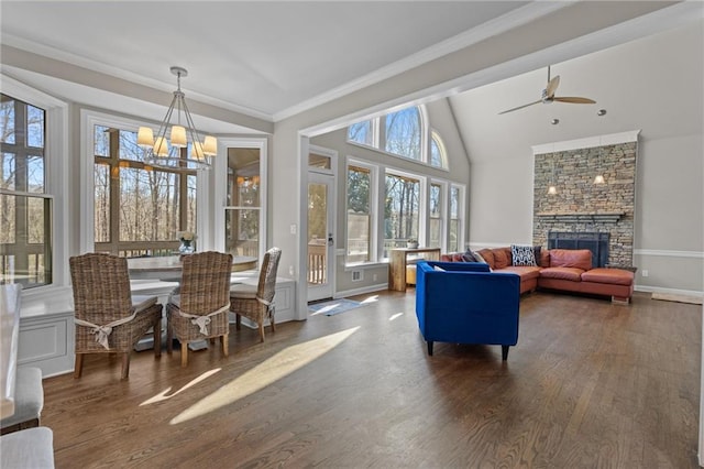 interior space featuring ceiling fan with notable chandelier, a stone fireplace, and vaulted ceiling