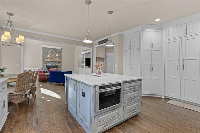 kitchen featuring pendant lighting, a fireplace, a center island, and white cabinets