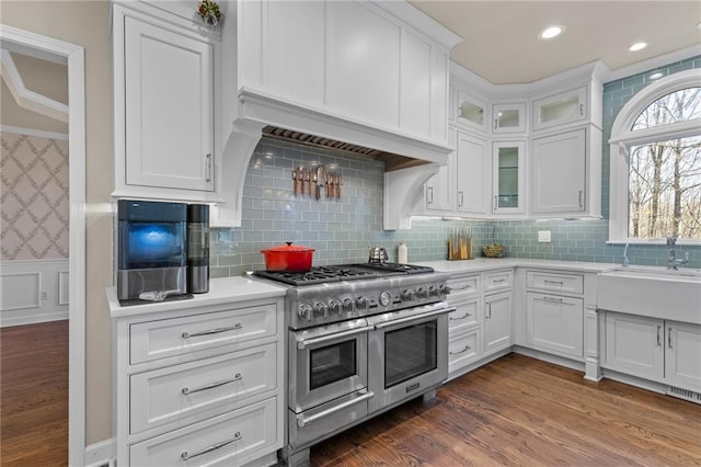 kitchen with premium range hood, white cabinets, dark hardwood / wood-style flooring, range with two ovens, and ornamental molding