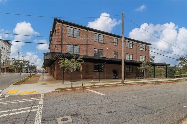back of property featuring uncovered parking and brick siding