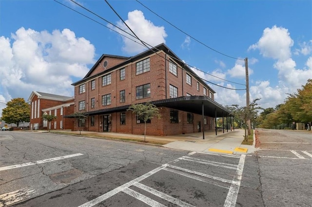 view of building exterior with covered and uncovered parking