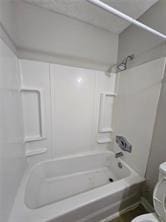 bathroom featuring shower / bathing tub combination and toilet