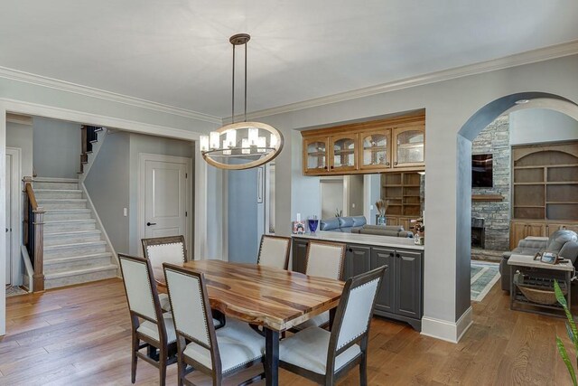 486 Gold Bullion Dr E, Dawsonville, GA 30534 - dining area featuring light wood finished floors, crown molding, stairway, a fireplace, and a chandelier