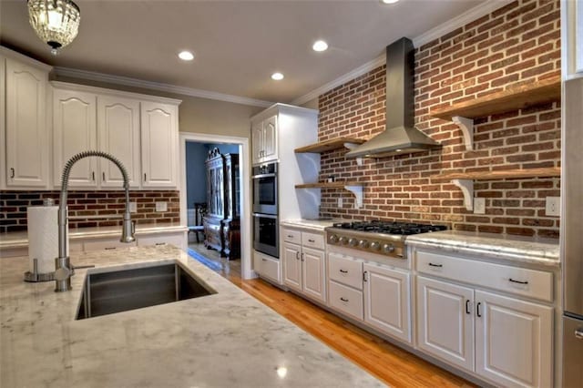 kitchen with wall chimney exhaust hood, stainless steel appliances, white cabinetry, open shelves, and a sink