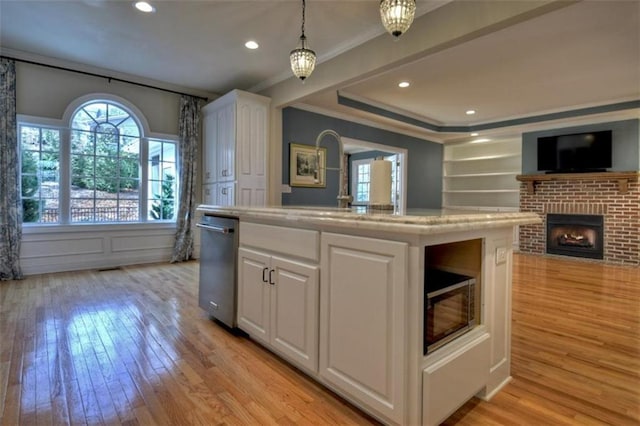 kitchen featuring open floor plan, light wood-style floors, white cabinetry, and dishwasher