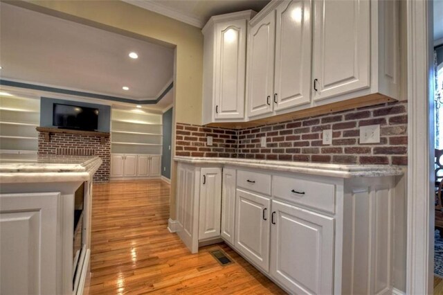 kitchen featuring recessed lighting, white cabinetry, light countertops, ornamental molding, and light wood-type flooring