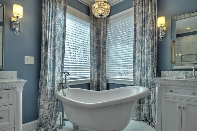 bathroom featuring marble finish floor, a freestanding bath, and vanity