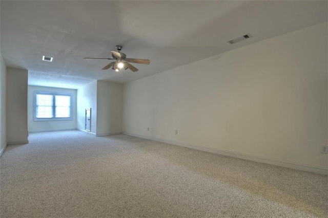 empty room with baseboards, a ceiling fan, visible vents, and light colored carpet