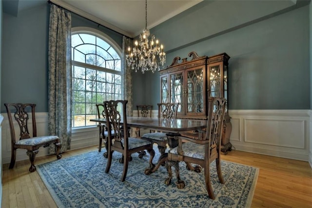 dining room featuring a wainscoted wall, light wood-style flooring, and a notable chandelier