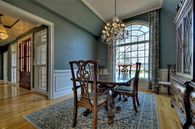 dining room featuring a wainscoted wall, a decorative wall, light wood-style flooring, and an inviting chandelier