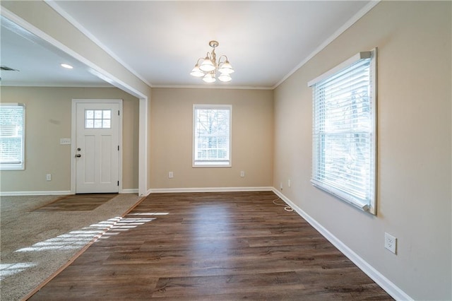 foyer entrance with crown molding, a notable chandelier, and a wealth of natural light