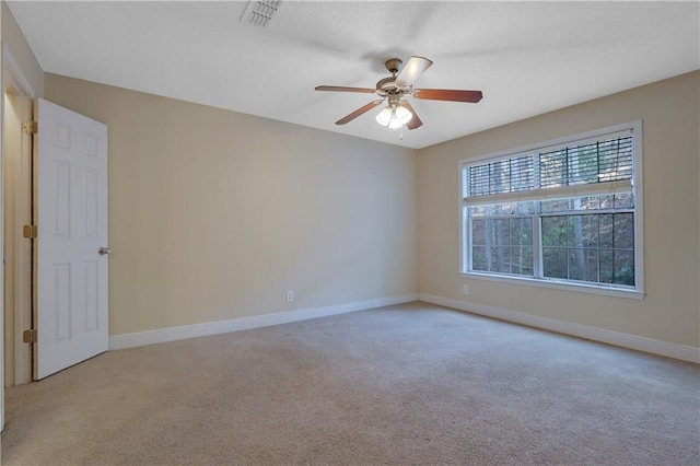 carpeted empty room featuring visible vents, ceiling fan, and baseboards