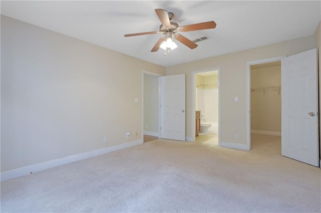 unfurnished bedroom with visible vents, baseboards, a closet, a walk in closet, and light colored carpet