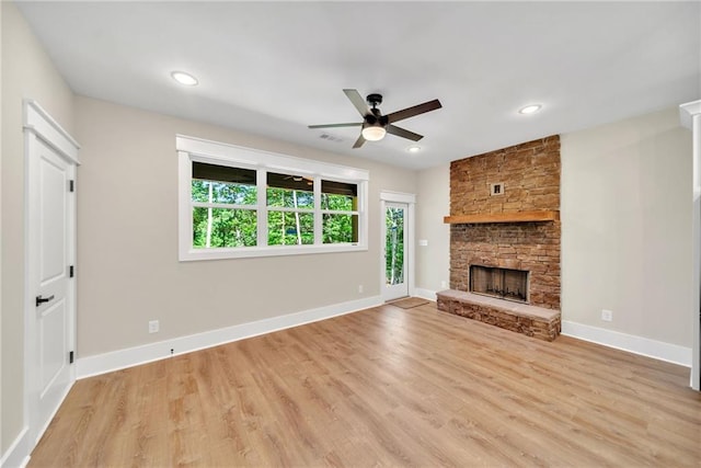 unfurnished living room with light hardwood / wood-style floors, ceiling fan, and a stone fireplace