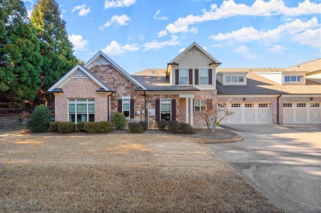 view of front of house with an attached garage, stone siding, driveway, and brick siding