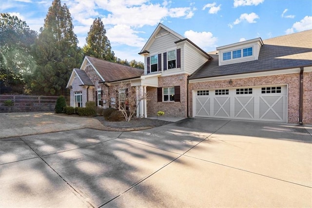 view of front facade featuring concrete driveway, brick siding, fence, and an attached garage