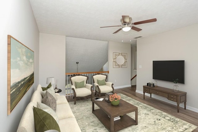 living room with ceiling fan, wood finished floors, baseboards, and a textured ceiling