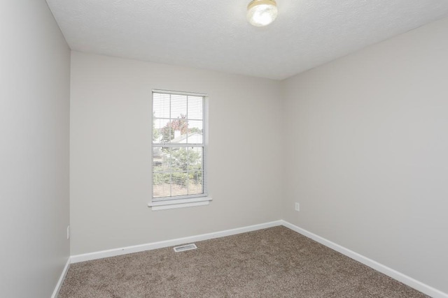 carpeted empty room with baseboards and a textured ceiling