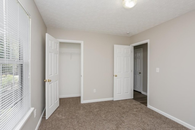 unfurnished bedroom featuring carpet flooring, baseboards, a closet, and a textured ceiling