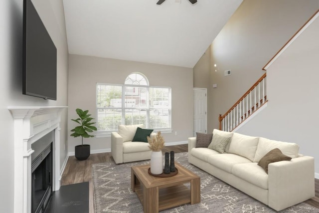 living area featuring high vaulted ceiling, wood finished floors, stairway, ceiling fan, and baseboards
