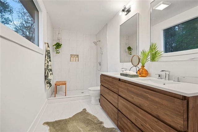 bathroom with vanity, toilet, and a tile shower