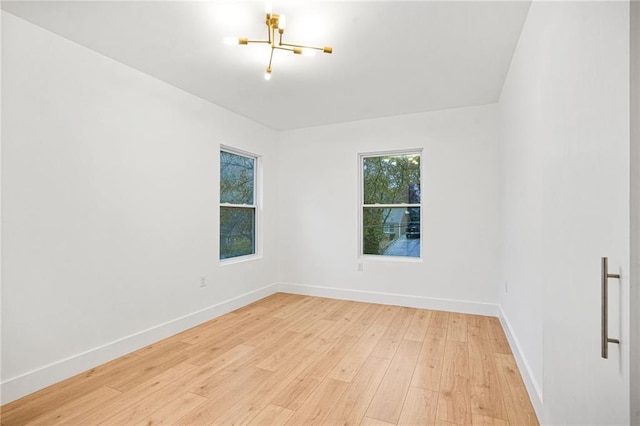 empty room featuring an inviting chandelier and light wood-type flooring